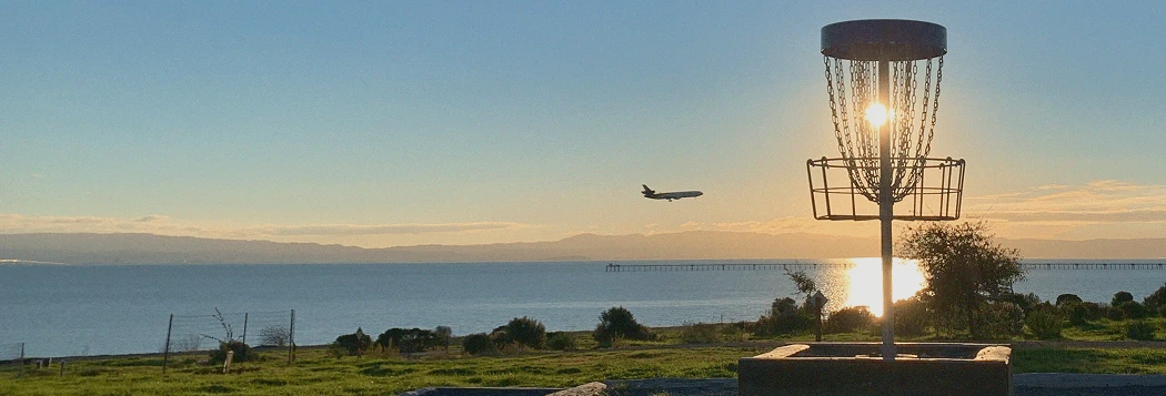Plane passing by a basket in beautiful Oyster Bay Disc Golf Course, San Leandro, California